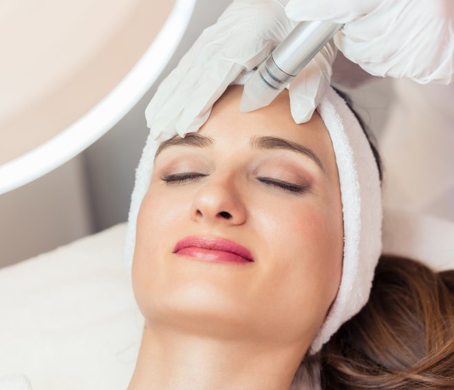 Close-up of the face of a beautiful woman smiling during facial treatment